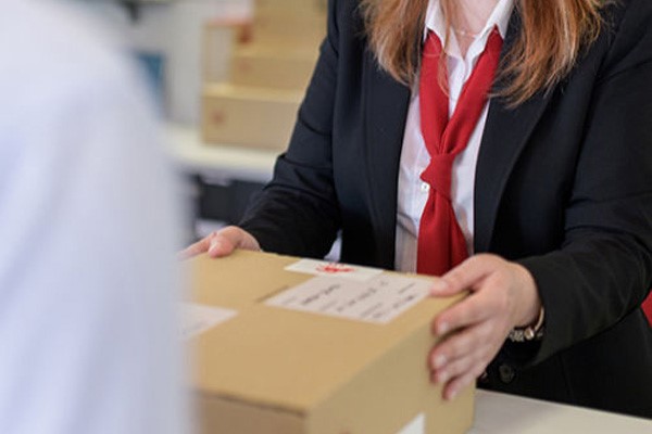 Senhora que trabalha numa Loja CTT, recebe uma encomenda.